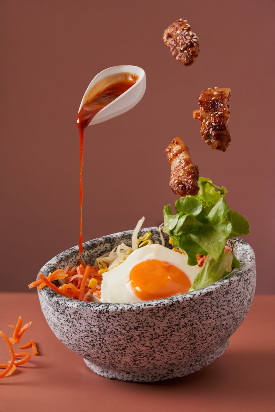 醬汁淋向拌飯，食材懸浮在畫面中