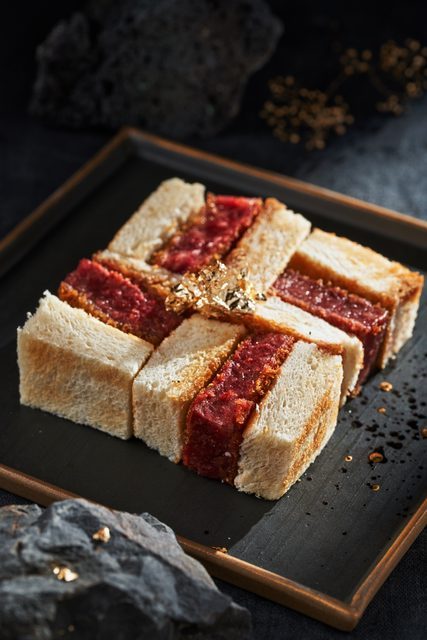深色托盤上排列切開的肉餡三明治