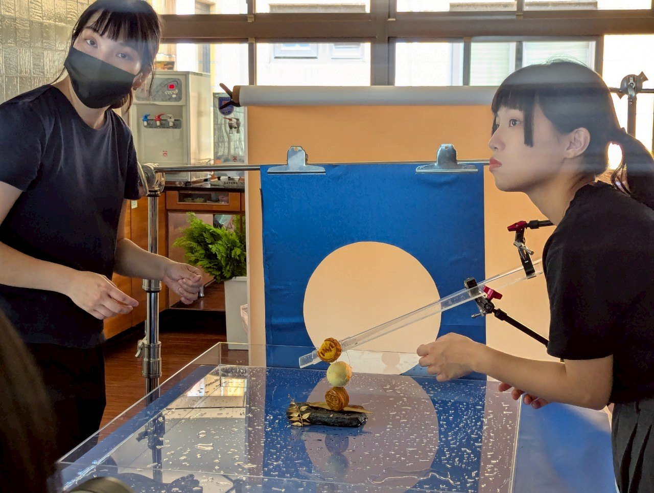 工作人員在圓月與藍色背景前調整月餅位置